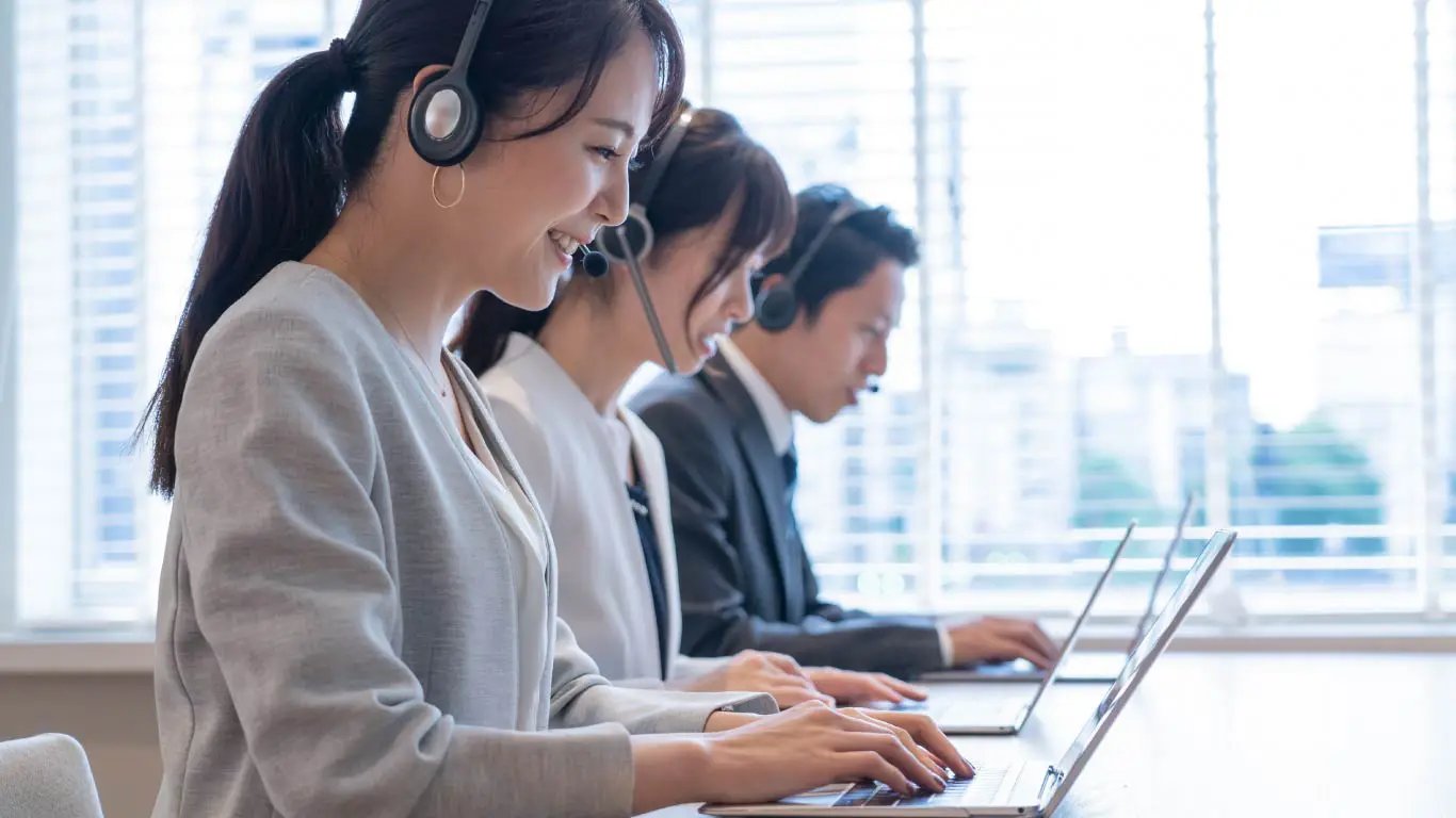 Three agents working with headsets on laptops