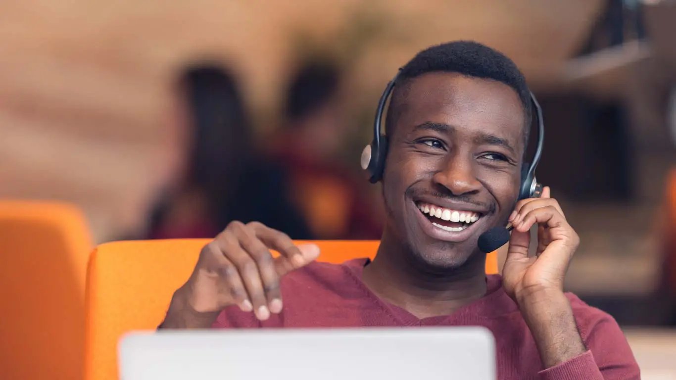 Happy employee talking on headset with laptop 