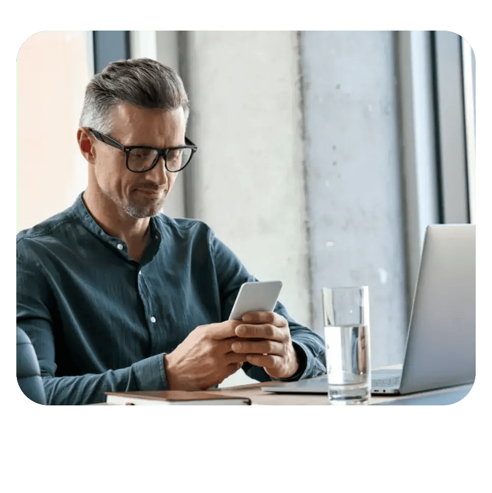 Professional man analyzing mobile data with a laptop and glass of water, representing mobile access to sales dashboards and call intelligence.