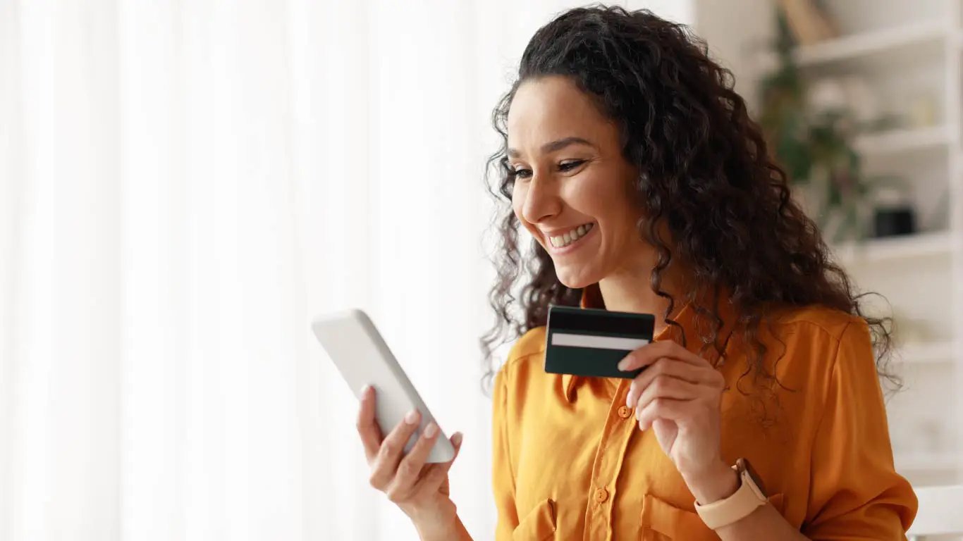 Cliente feliz com cartão de crédito olhando para o smartphone