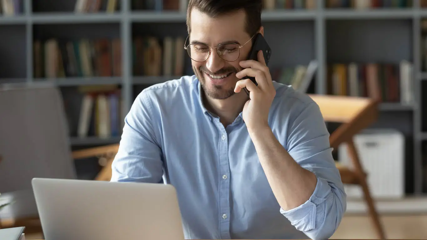 Homem feliz com telefone e notebook
