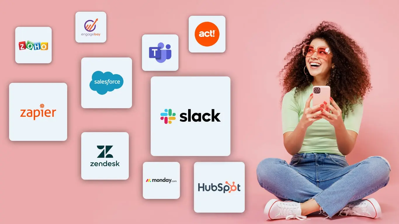 Happy lady sits holding a phone and looking on the logo cloud of the available business phone system integrations