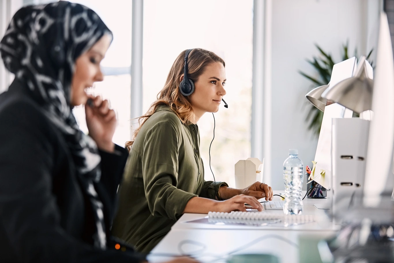 woman-on-headset-looking-at-computer-with-another-agent